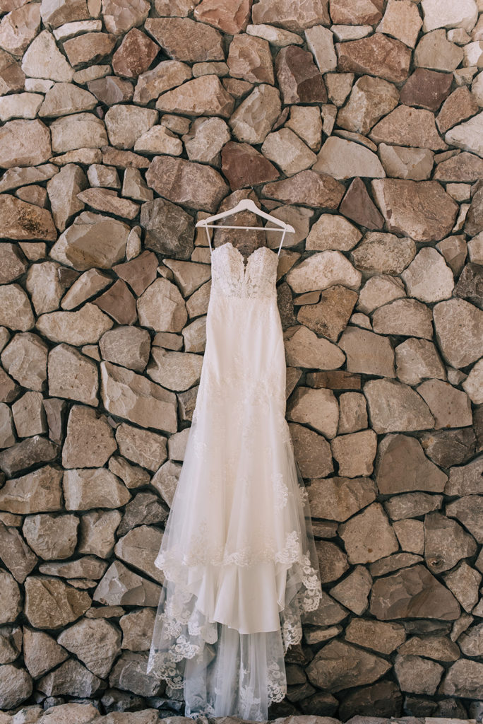 Lace wedding dress hanging on a stone wall