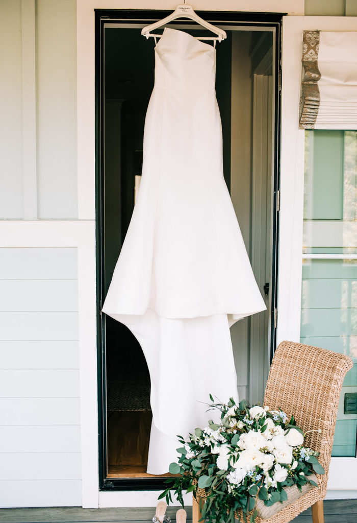 Bride's dress hanging on a door with flowers and shoes