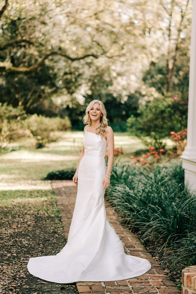 Bride standing in her wedding dress laughing 