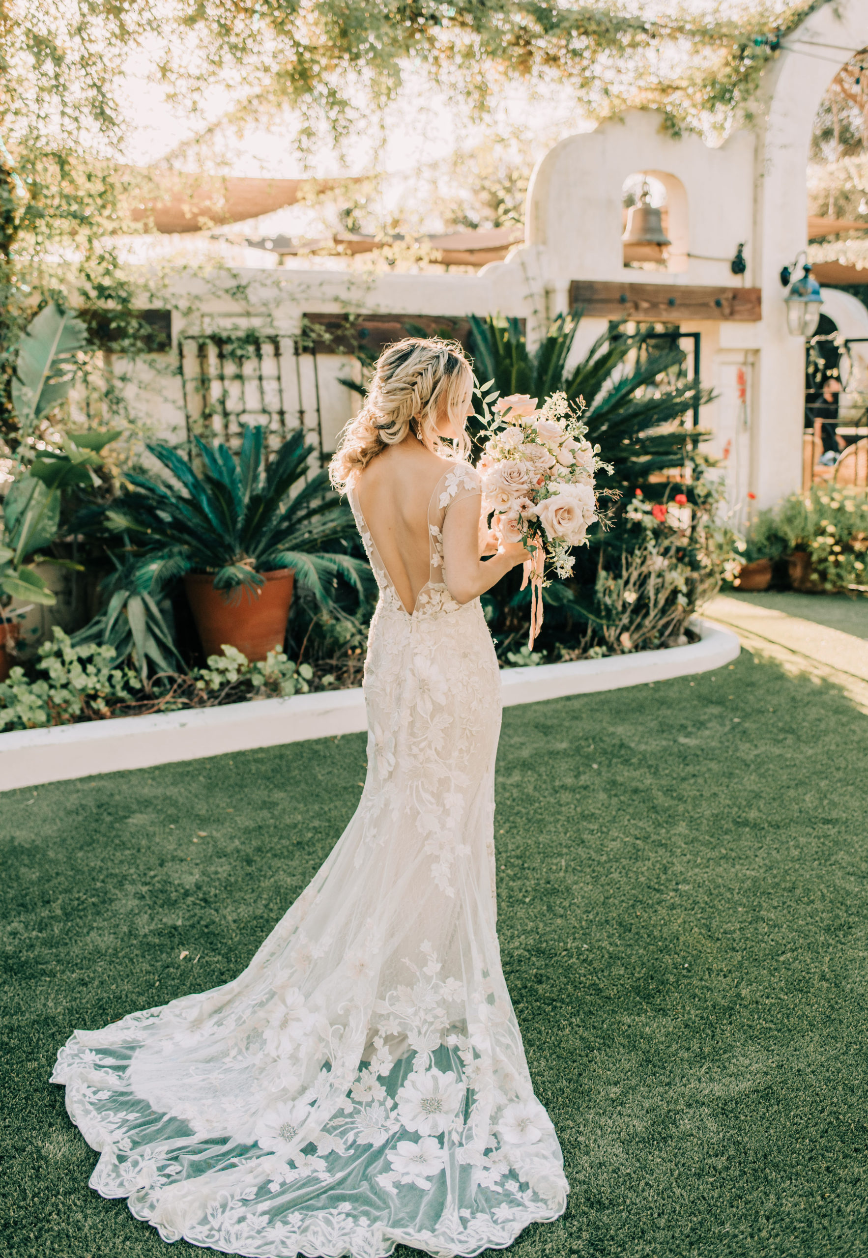 Bride standing facing smelling her flowers at her wedding venue, Tivoli Italian Villa