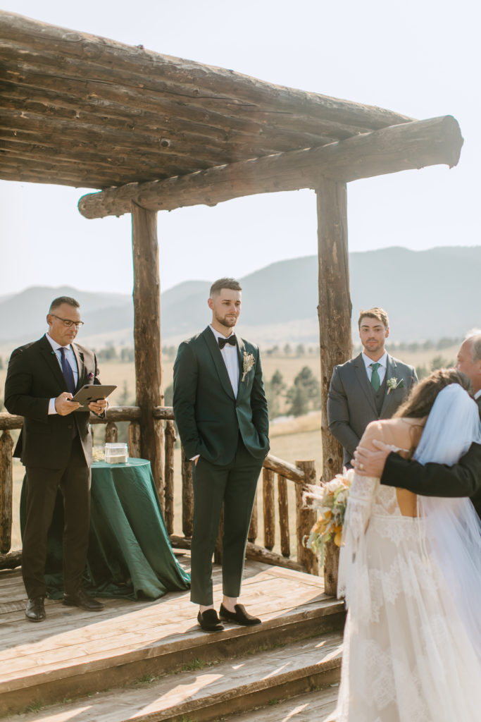 The groom getting emotional watching the bride and her father standing in front of him during the  Spruce Mountain Ranch wedding