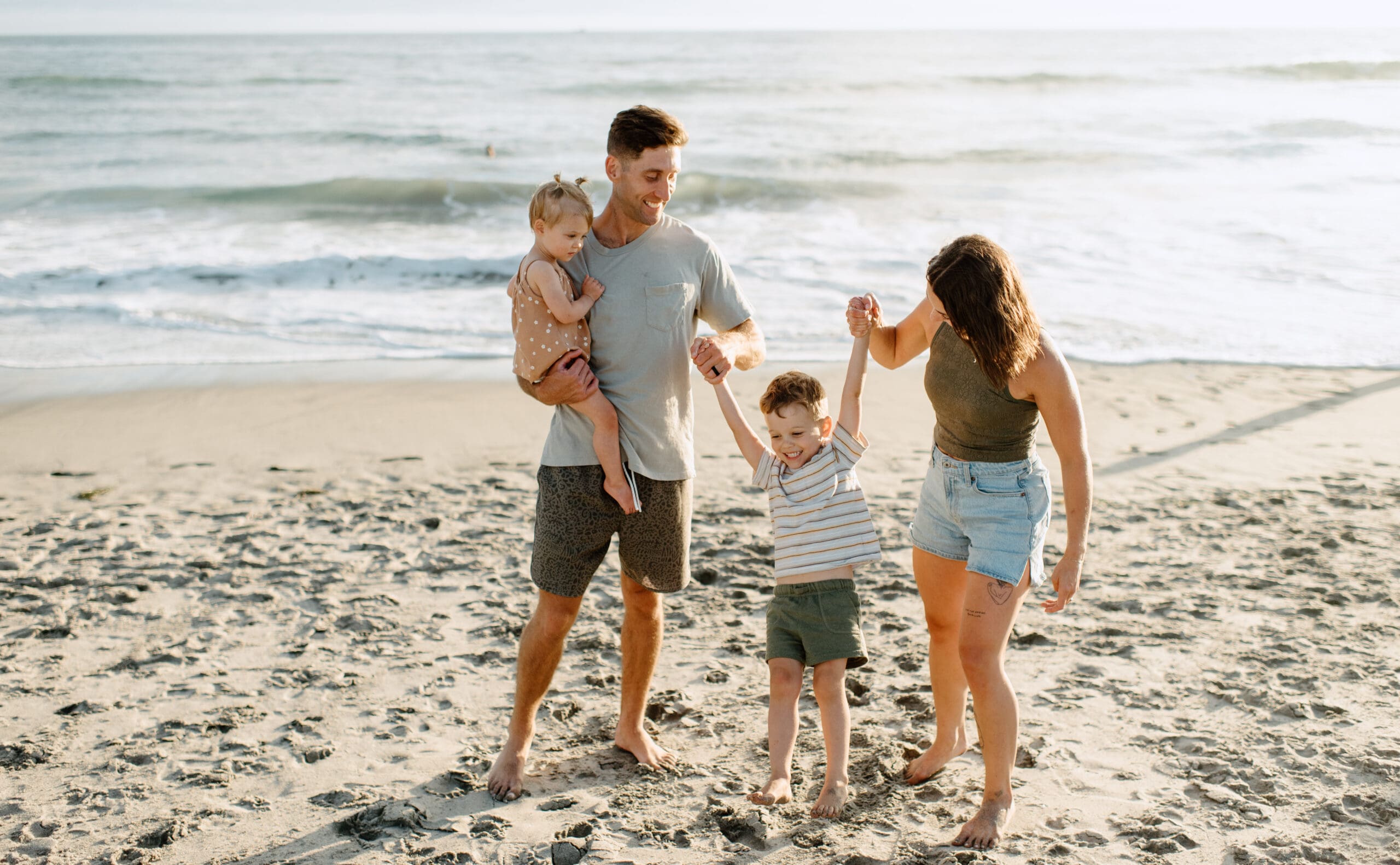 Oceanside photographer capturing  a family of four playing on the beach