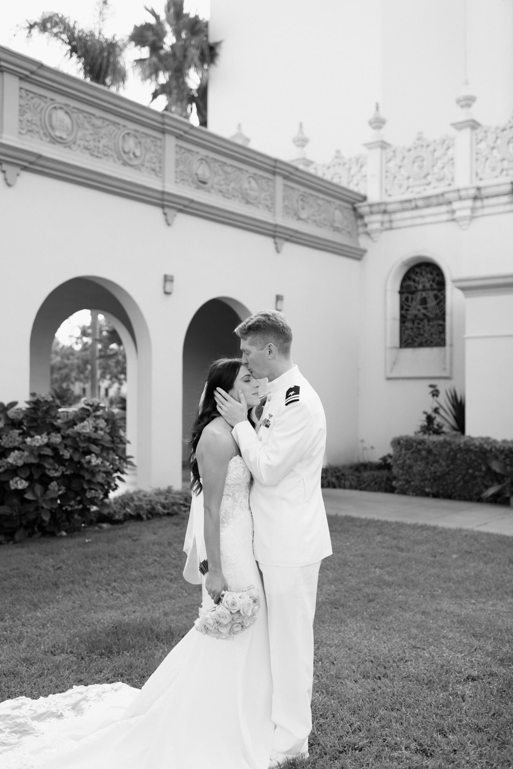 The groom kissing the bride's forehead during portraits
